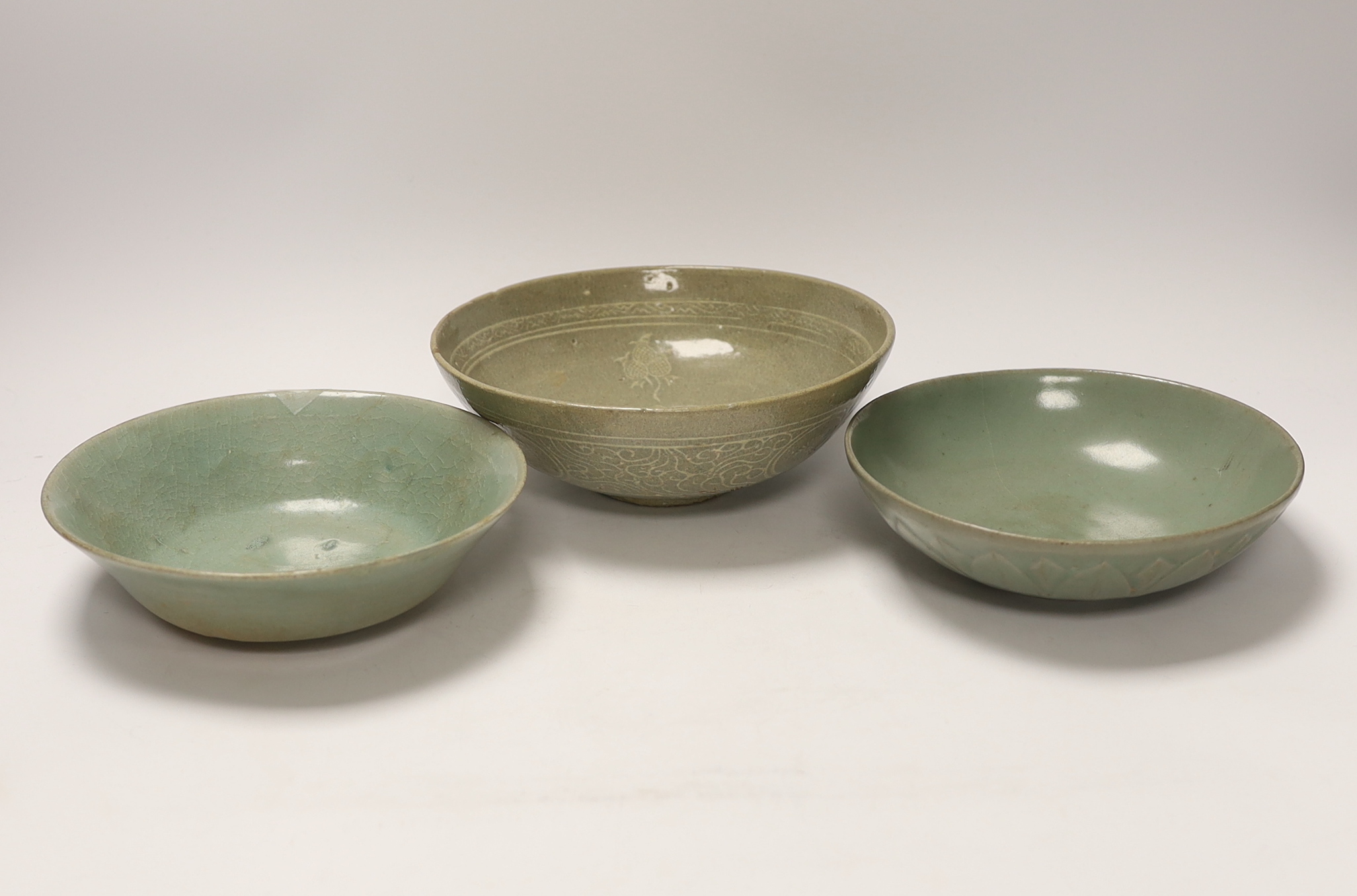 Two Korean celadon bowls, Goryeo dynasty (11th/12th century), the first carved with lotus petals to the underside, the second with fine crackle to the glaze, and a Korean slip-decorated celadon bowl (11th/12th century),